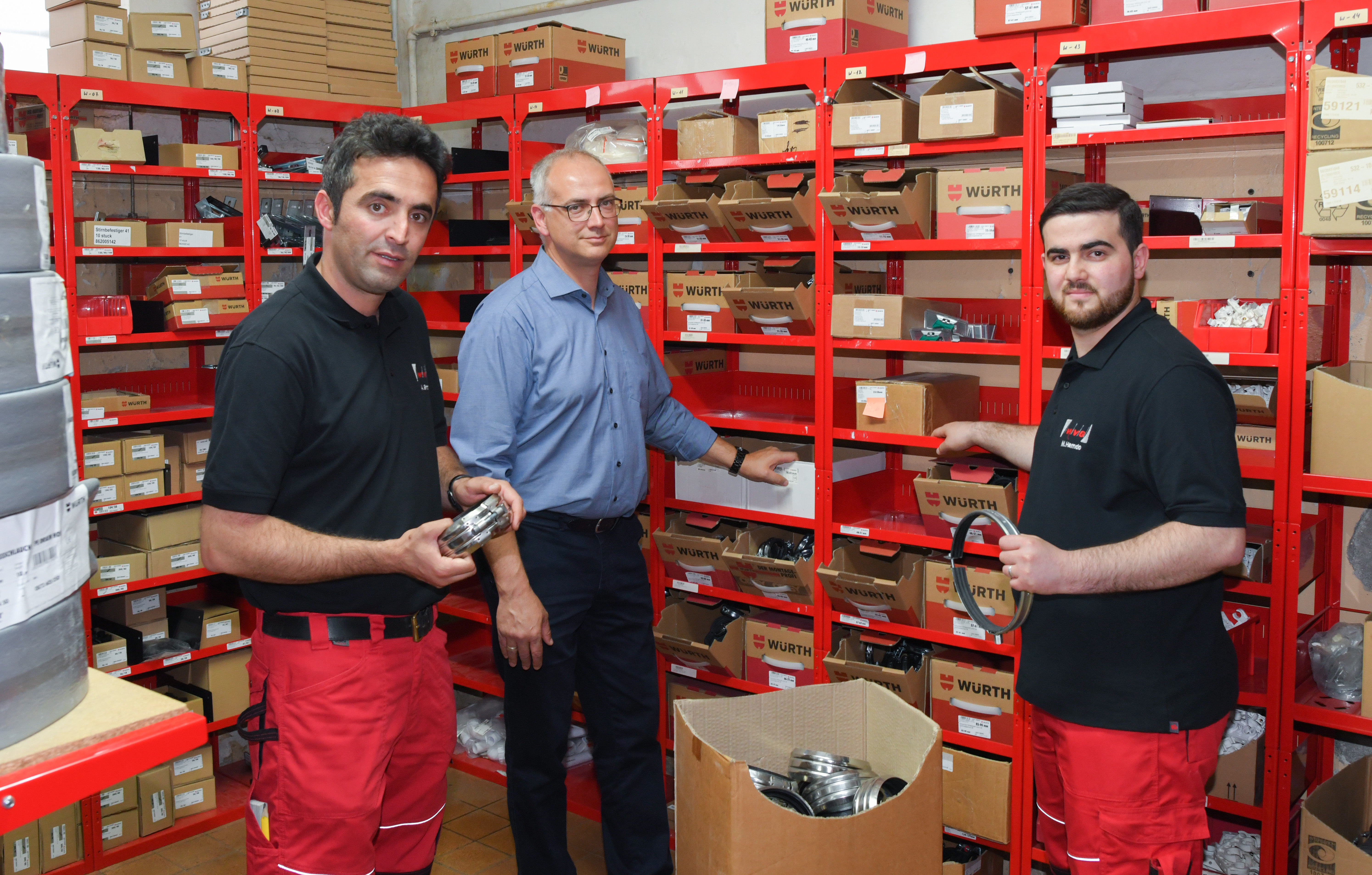 Asad Shirzad (l-r) aus dem Iran, Mario Ruckdäschel, Böroleiter der Wärmeversorgungsgesellschaft mbH und Mohamad Hamdo aus Syrien, Auszubildender, stehen nach einer Pressekonferenz zur Integration von Geflüchteten in den Arbeitsmarkt in Brandenburg am Unternehmensstandort der Wärmeversorgungsgesellschaft mbH in einem Materiallager.