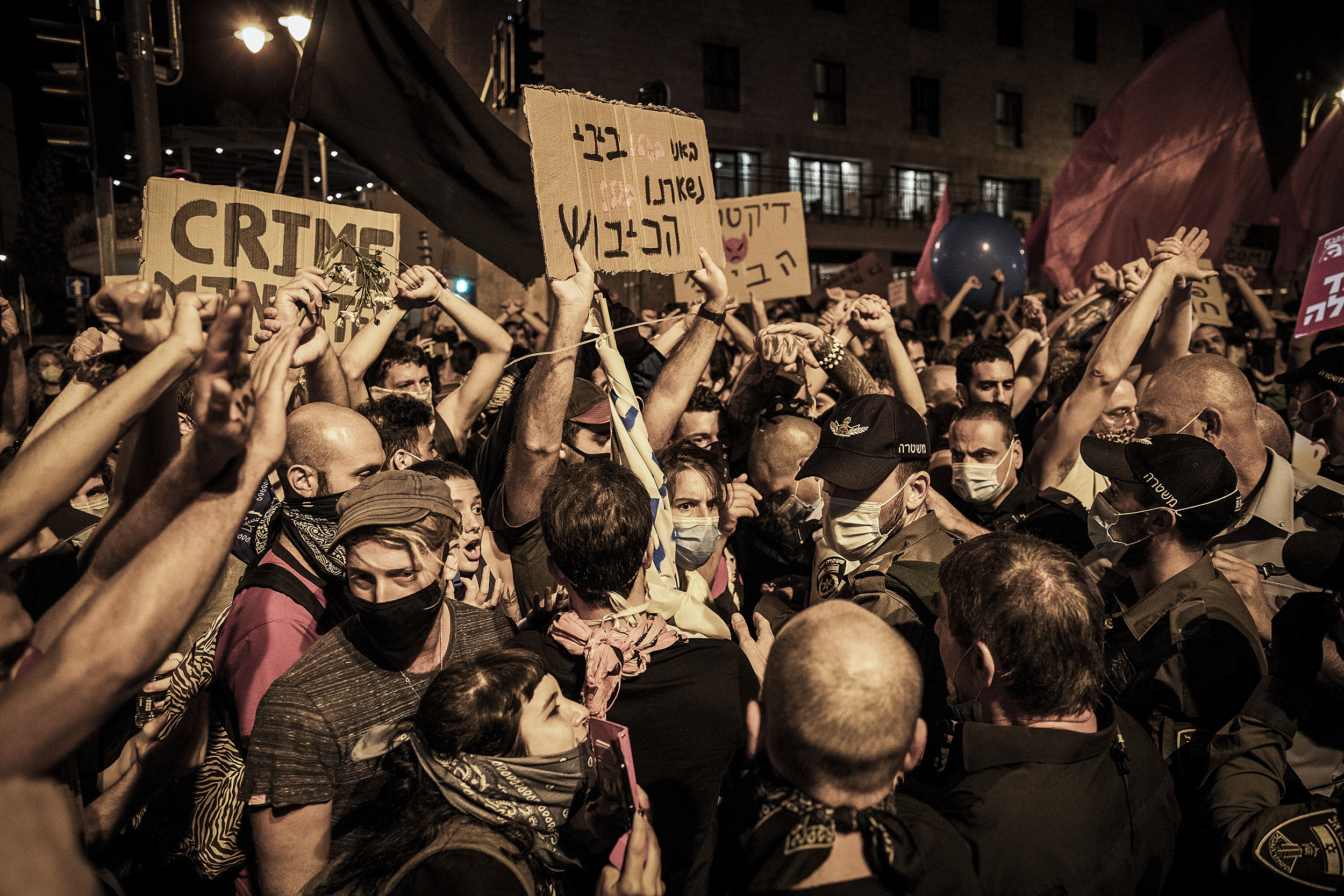 Demonstranten stehen mit Plakaten mit der Aufschrift "Crime" bei Protesten gegen den israelischen Ministerpräsidenten in der Nähe seiner offiziellen Residenz
