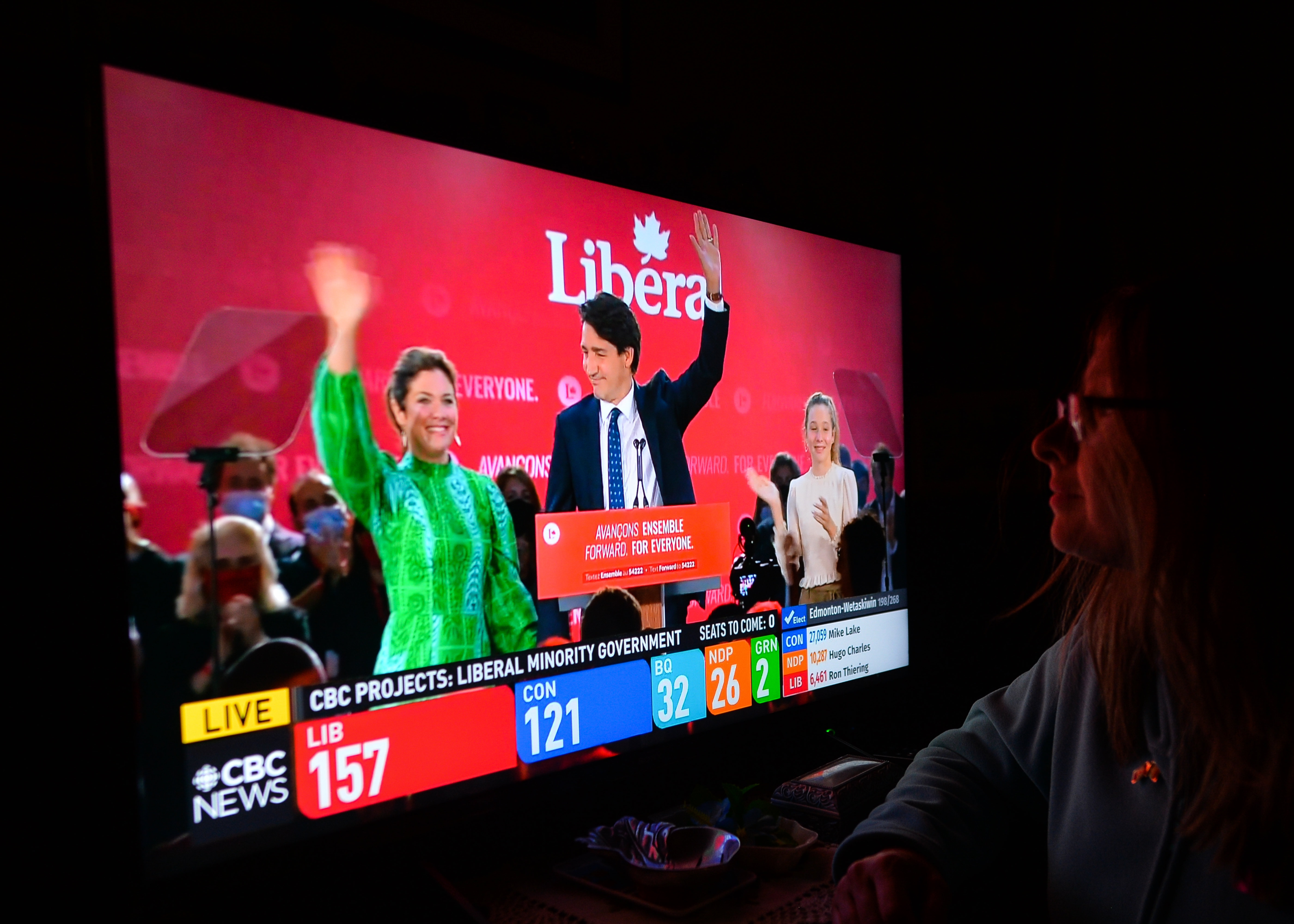 Eine Frau schaut eine Wahlsendun von CTS News auf dem Fernseher, die einen feiernden Justin Trudeau zeigt.