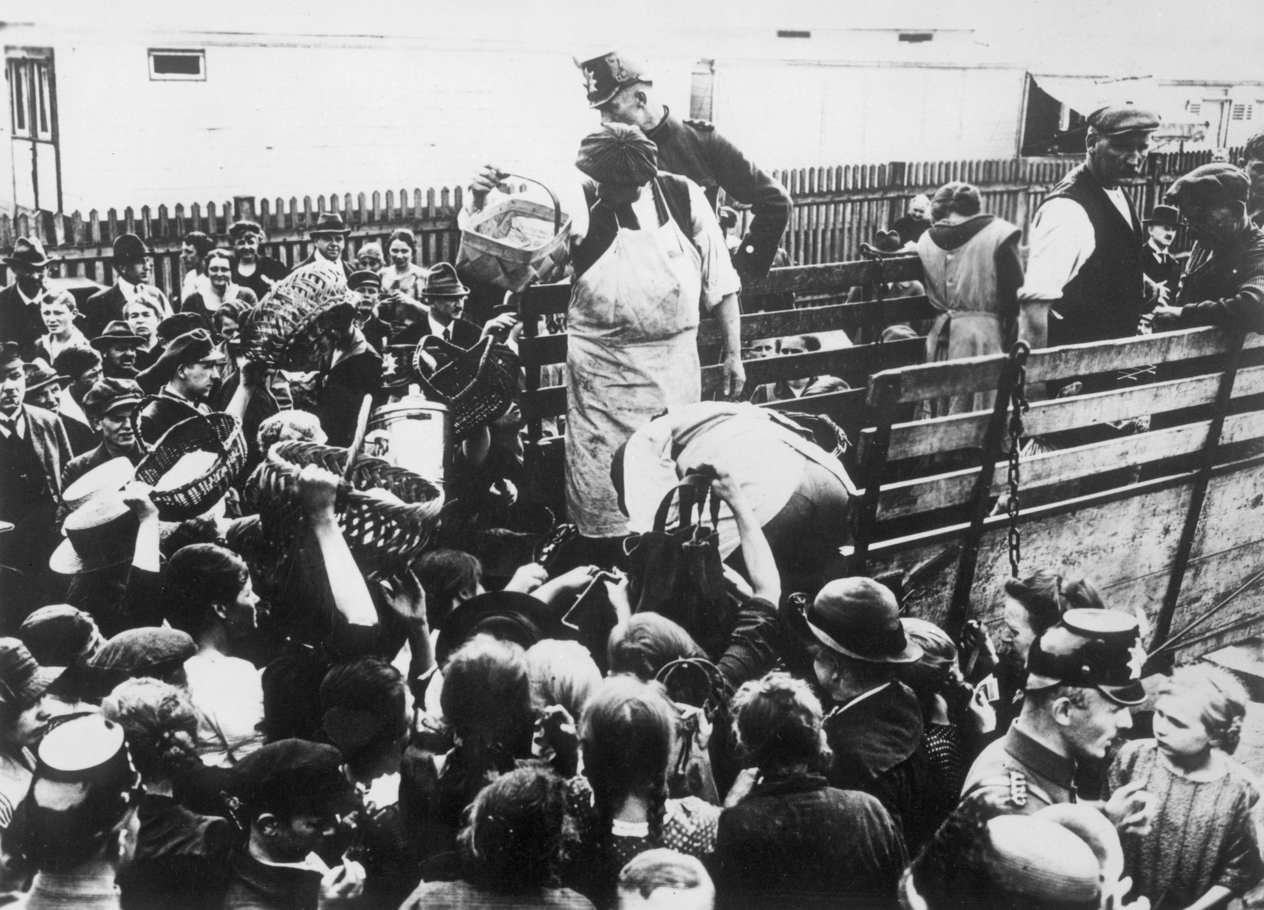 Inflation 1923: Berliner Bevölkerung umlagert einen Kartoffelhändler, der seine Ware vom Wagen unter Polizeischutz verkauft.