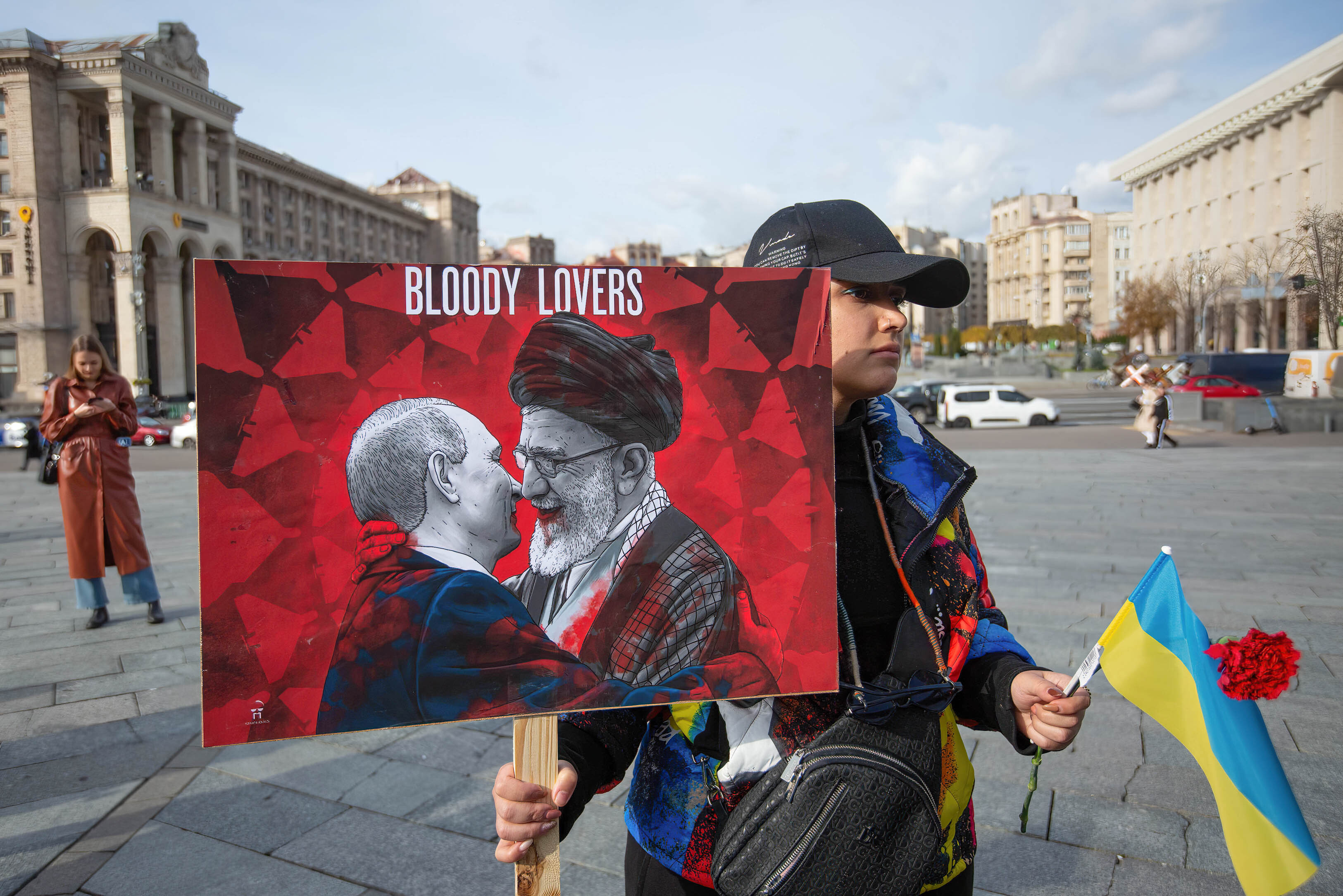Ukrainischer Demonstrant hält Bild von Putin und Ayatollah beim Küssen
