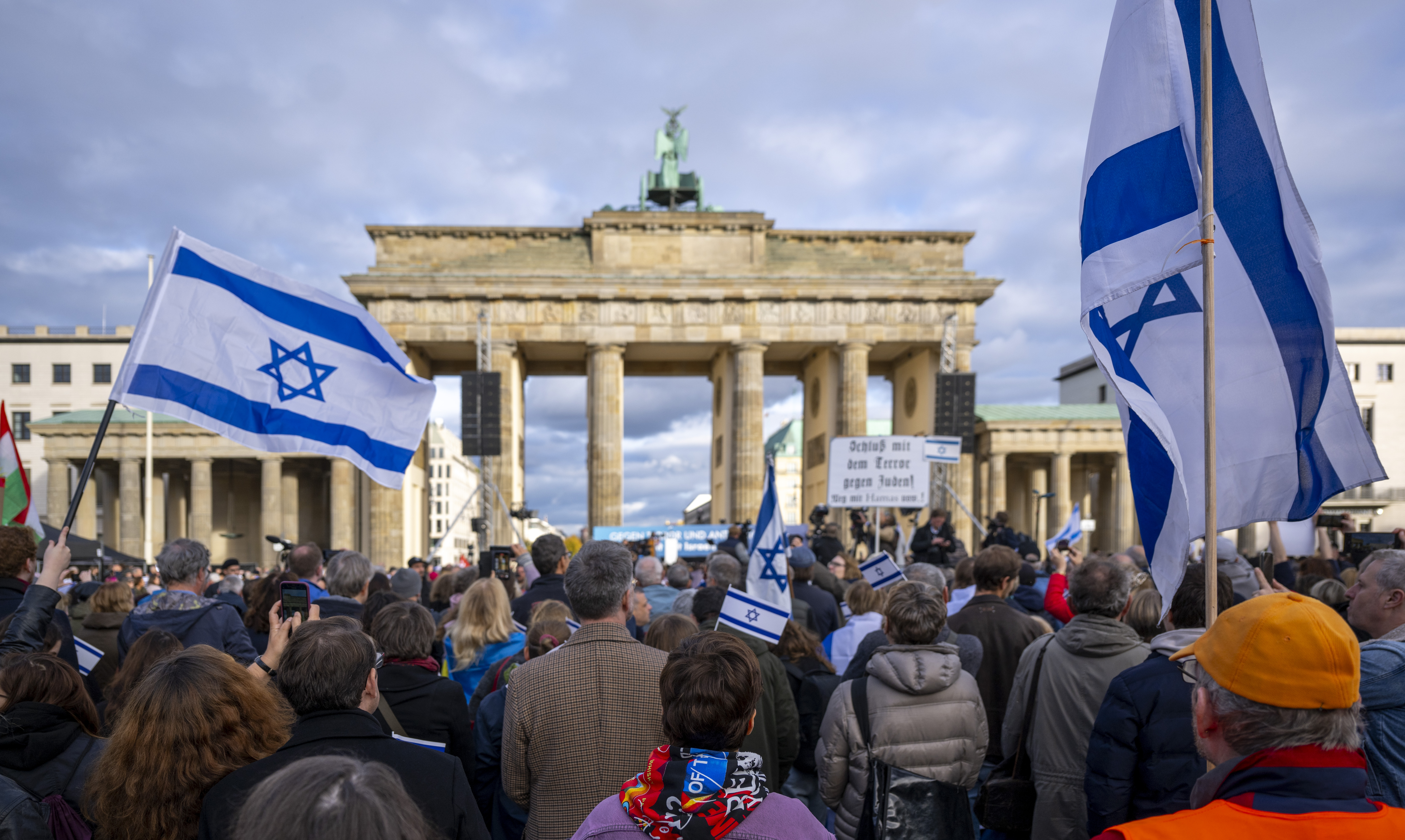 Teilnehmer der Kundgebung „Aufstehen gegen Terror, Hass und Antisemitismus – in Solidarität und Mitgefühl mit Israel“ vor dem Brandenburger Tor schwenken israelische Flaggen.