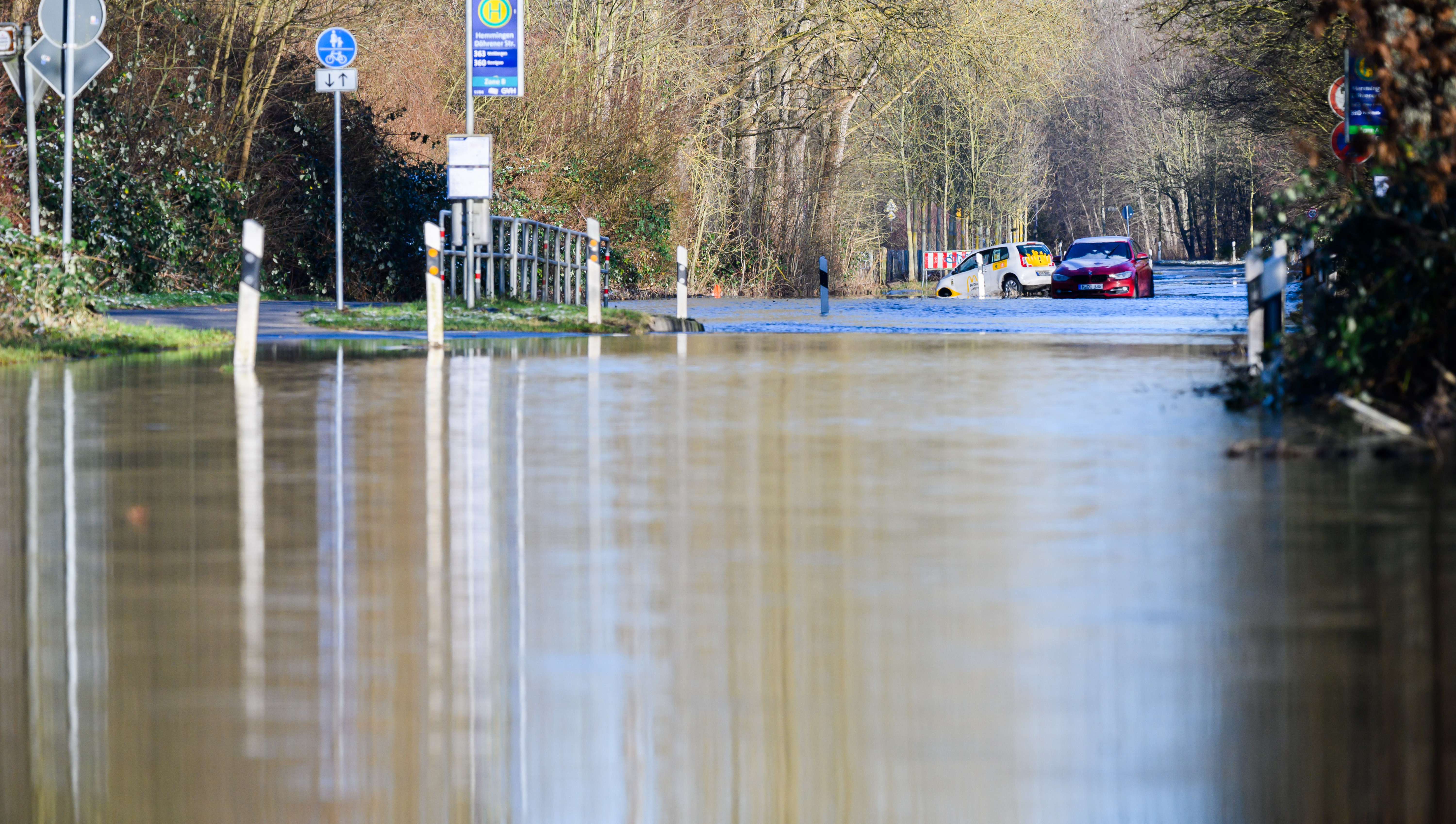 Zwei Autos stehen auf einer von dem über die Ufer getretenen Fluss Leine überfluteten Straße zwischen Hannover und Hemmingen in der Region Hannover. 