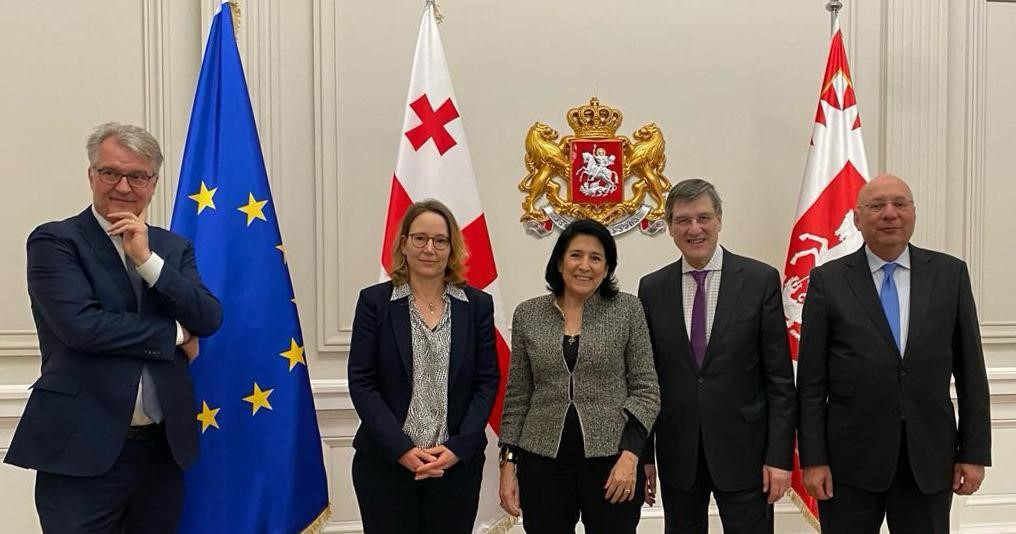 Die Präsidentin Salome Surabitschwili steht mit Vertretern der Stiftung vor georgischen und EU Flaggen