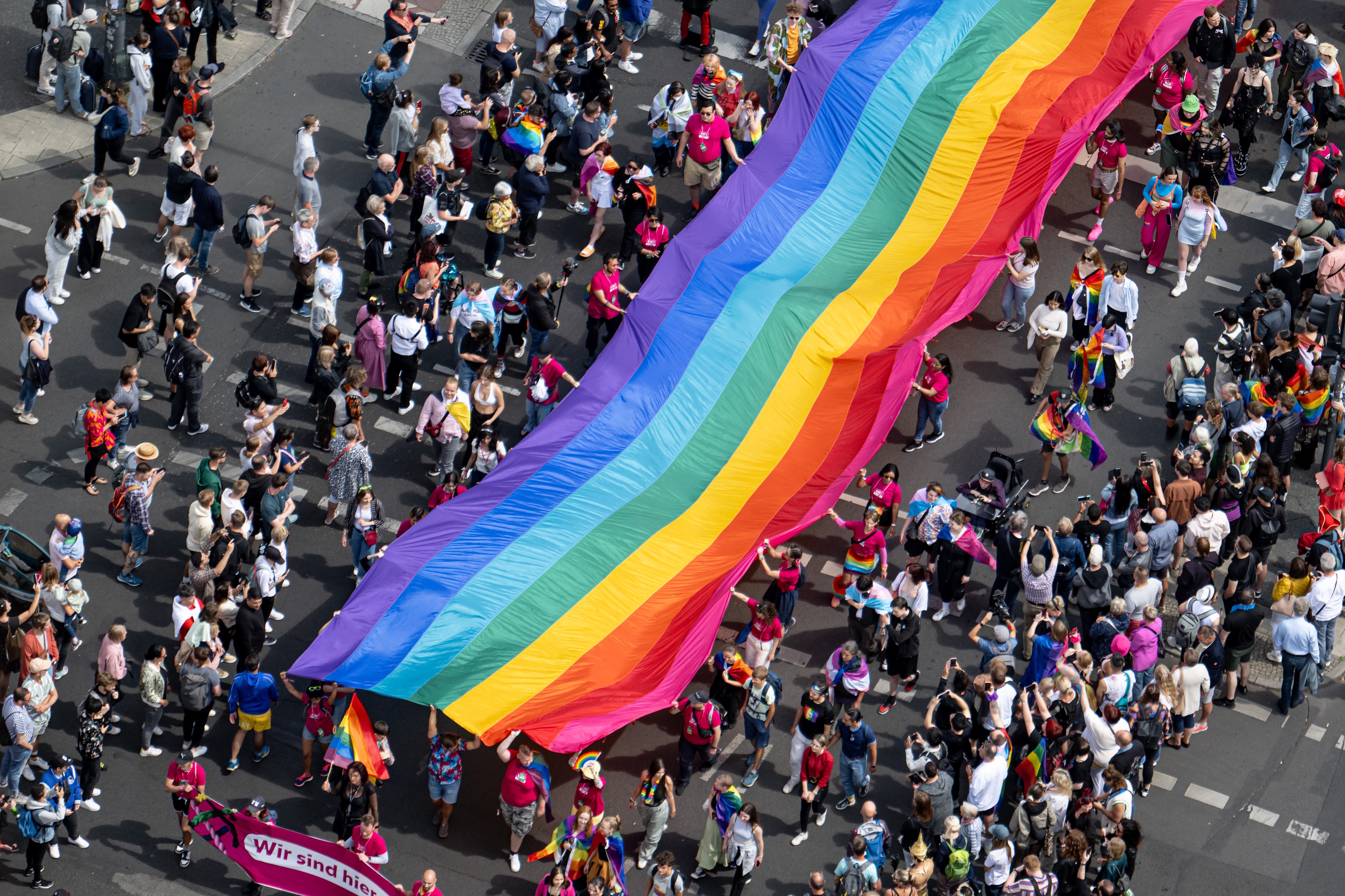 Menschen ziehen auf der 45. Berlin Pride-Parade zum Christopher Street Day (CSD) mit einer überdimensionalen Regenbogenfahne durch die Stadt. 