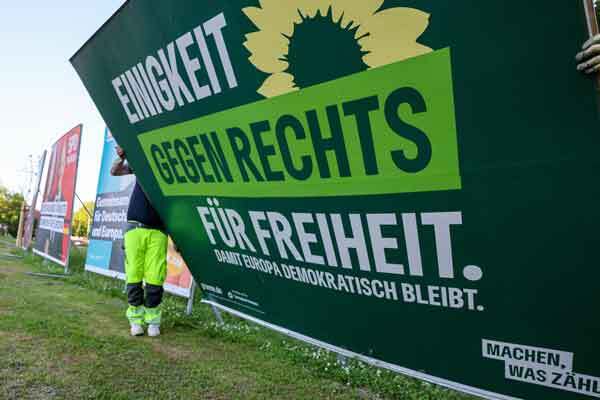 Zwei Mitarbeiter einer Firma für Werbeaufsteller bauen ein Wahlplakat der Partei „Bündnis 90/Die Grünen“ nach der Europawahl ab