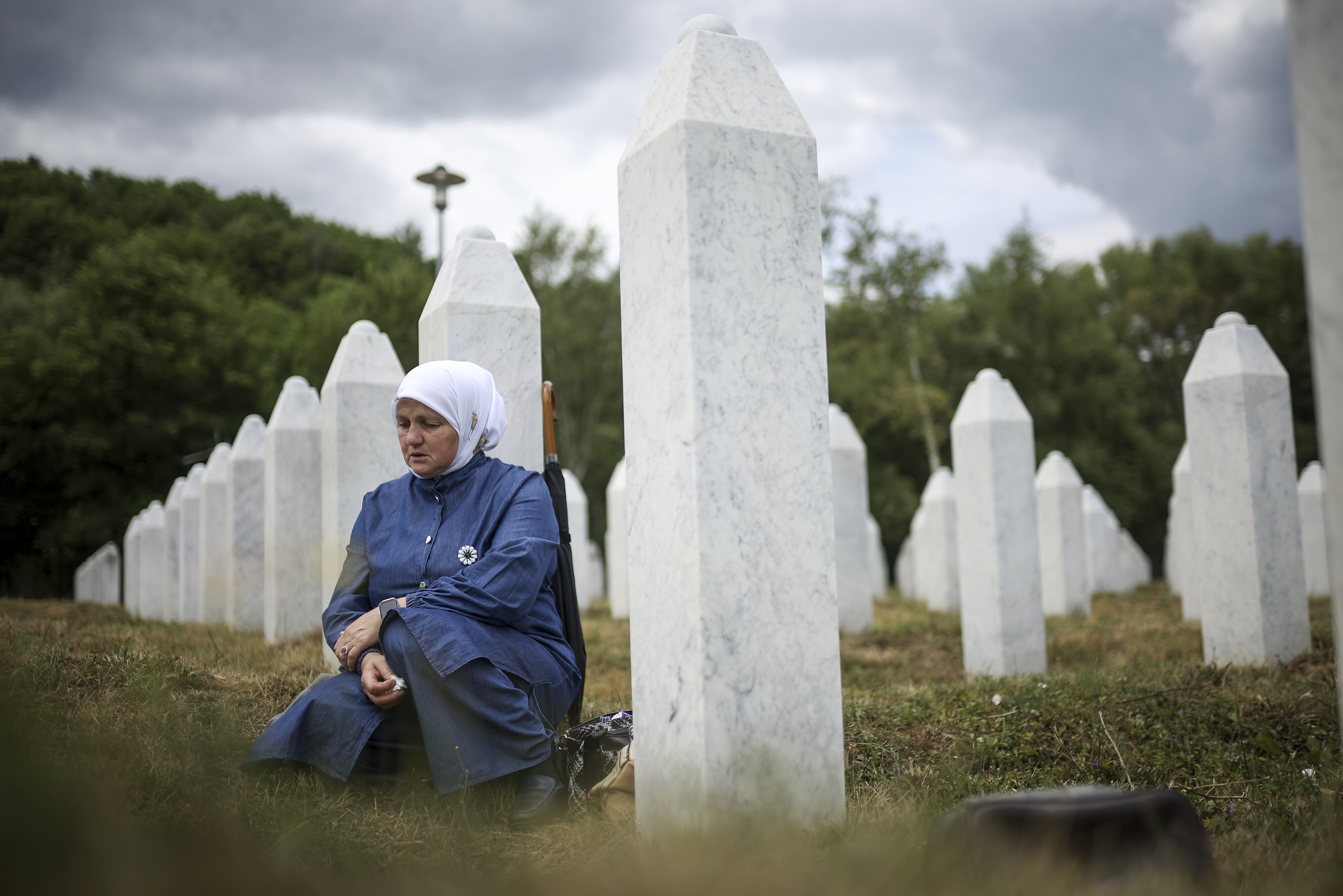 A woman mourns next to the grave of her relative, a victim of the Srebrenica genocide.