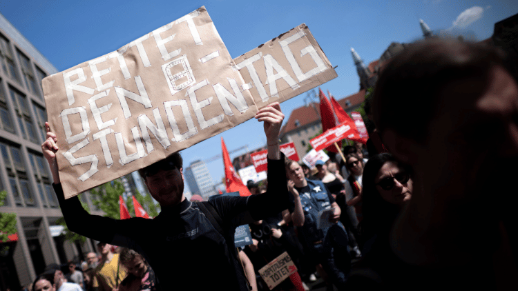 Demonstranten mit Plakat Rettet den 8-Stunden-Tag 