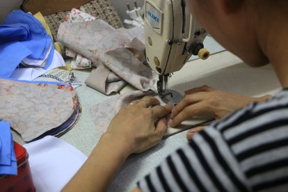 Eine Frau, die im Frauenhaus lebt, stellt handgemachte Masken zum Verkauf her