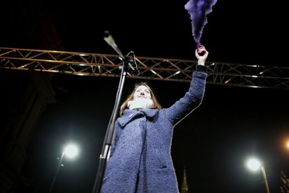 Anna Donáth holds up the purple smoke grenade after her speech