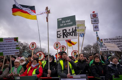 Teilnehmer der Demonstration der Landwirtinnen und Landwirte halten während der Kundgebung Schilder und Transparente hoch.