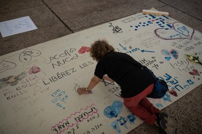 Eine israelische Frau schreibt eine Botschaft der Liebe und Unterstützung auf ein auf dem Boden ausgelegtes Banner für die geschätzten 200 israelischen Geiseln, die in Gaza in Tel Aviv, Israel, festgehalten werden.