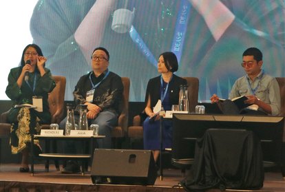 The second panel of the conference. Four people are sitting in single chairs in front of a big screen on a stage. They are Dr. Tricia Yeoh (Moderator), Nicholas Khaw (Panelist), Julia Goh (Panelist), Dr. Zouhair Rosli (Panelist).