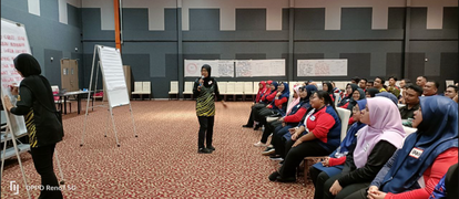 A batch of training participants paying close attention to the trainer's explanation from the front of the room. Another trainer is busy writing on one of the two small whiteboards