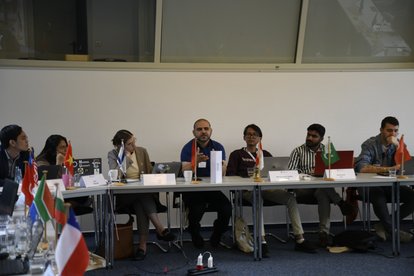 Hafizh Nabiyyin (black shirt with glasses) sitting on a long table amidst other IAF participants.