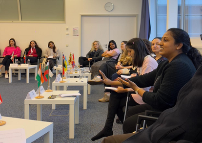 Kasturi, sitting on the far right of the picture, is explaining something to the forum. The other participants sit around her. Some looking at her, some listening while taking notes.