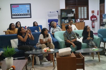 FNF's staff and partners were sitting in sofas. Their eyes were focused to something in front of them, where someone was giving a presentation.