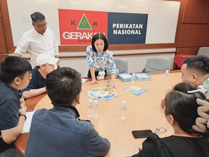 Mary, Program Manager at FNF Thailand, is demonstrating the mechanics of the SIM Democracy game to the representatives of GERAKAN Party and its youth wing.