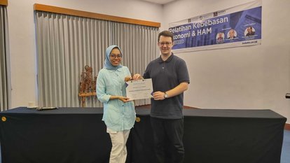 Seorang peserta berfoto bersama Dr. Stefan Diederich (Project Director FNF Indonesia). Keduanya tampak memegang sertifikat milik peserta secara bersama-sama.