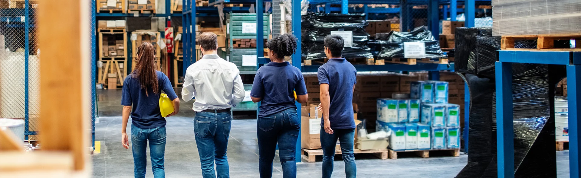Symbolbild für Soziale Marktwirtschaft: Man sieht eine große Lagerhalle eines Unternehmens mit vier Mitarbeitenden
