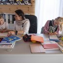 Mutter mit ihren Kindern beim Homeschooling