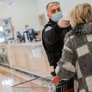 Eine Frau wird vor dem Betreten des Supermarktes auf Fieber kontrolliert.