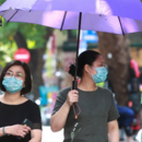 Frauen mit Gesichtsmasken gehen in Hanoi auf die Straße