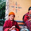 A man in Red Robe Sitting beside a Green Metal Fence