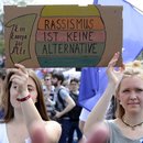 Zwei Frauen mit einem Schild "Rassissmus ist keine ALternative" stehen bei einer Demonstration für Europa