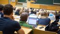 Studierende sitzen mit Laptops in einer Vorlesung.
