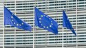 Drei Fahnen der Europäischen Union wehen vor dem Gebäude der EU-Kommission. 