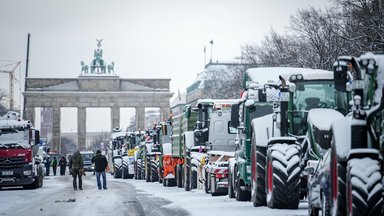 Zahlreiche schneebedeckte Traktoren stehen auf der Straße des 17. Juni vor dem Brandenburger Tor.
