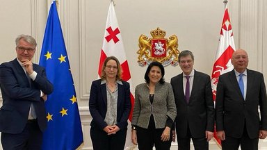 Die Präsidentin Salome Surabitschwili steht mit Vertretern der Stiftung vor georgischen und EU Flaggen