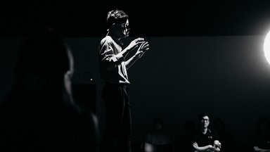 Teilnehmer von “Open Mic” 2022, der mit einer Maske auftritt, um anonym sprechen zu können 