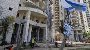 Ein israelischer Sicherheitsbeamter steht am Eingang eines Wohngebäudes, das von einer aus dem Iran abgefeuerten Rakete getroffen wurde