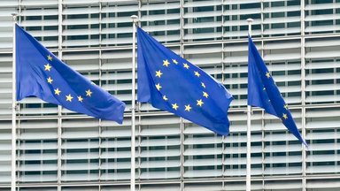 Drei Fahnen der Europäischen Union wehen vor dem Gebäude der EU-Kommission. 