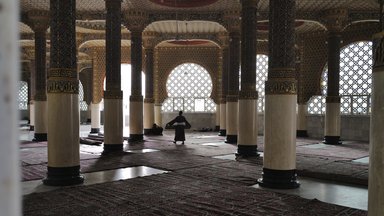 Ein Mann trägt einen Teppich in einem Gebetsraum in der Großen Moschee in Touba, Senegal,