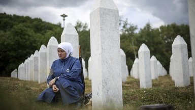 A woman mourns next to the grave of her relative, a victim of the Srebrenica genocide.