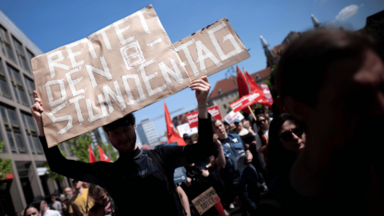 Demonstranten mit Plakat Rettet den 8-Stunden-Tag 